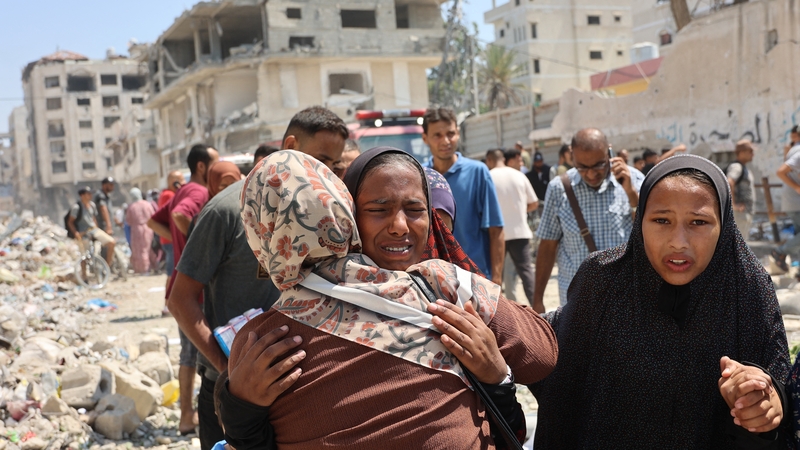 Daoine ag comhfhortú a chéile tar éis an ionsaí a rinne na hIosraelaigh ar scoil i gCathair Gaza ar maidin inniu