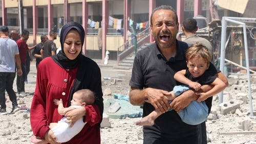 People flee with their young children after 12 people were killed in an Israeli strike on a school in Gaza City