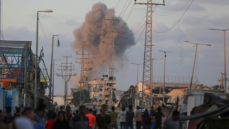 Palestinians watch the smoke rising after the Israeli attack on the Nuseirat refugee camp, in Deir al Balah