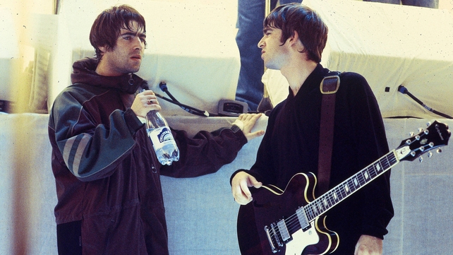 Liam Gallagher and Noel Gallagher, talking on the set of a UK TV show, 1996. Photo by Des Willie/Redferns.