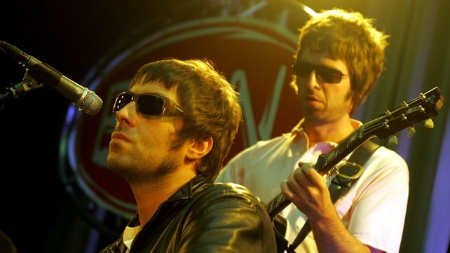 Liam and Noel Gallagher performing live onstage in 2005. Photo by Paul Bergen/Redferns.