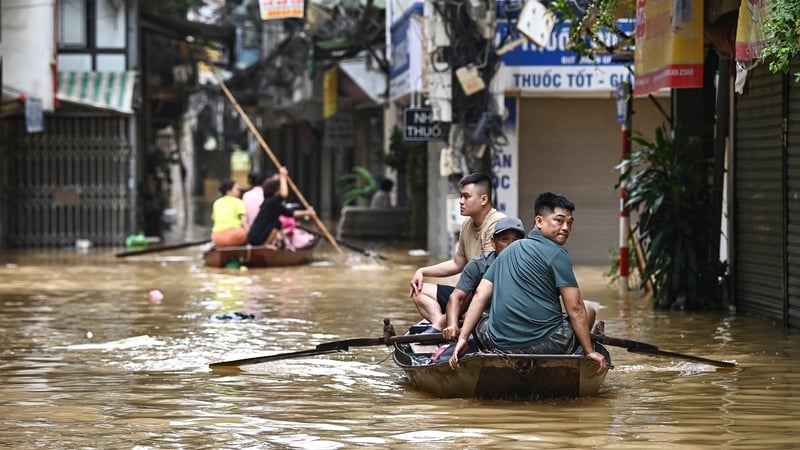 People wade through flood waters on a boat in Hanoi