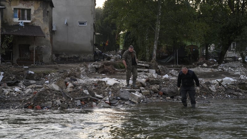 A man enters into the Morawka river to clean his boots after the flood left debris and damaged houses in Stronie Slaskie, Poland
