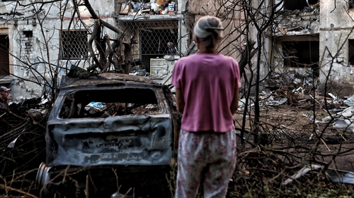 A woman looks at a residential building that was damaged in the Shevchenkivskyi district in Ukraine over the weekend