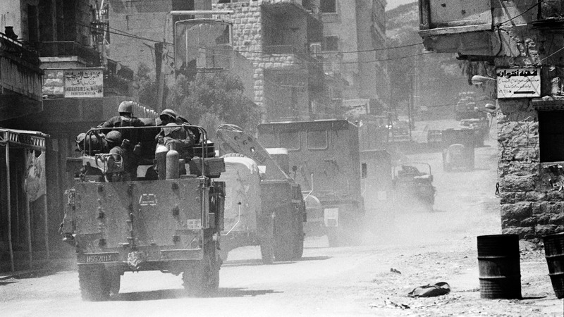 Israeli soldiers in armoured vehicles travel past houses as they move through a village in the Bekaa Valley during the 1982 Israeli invasion of Lebanon