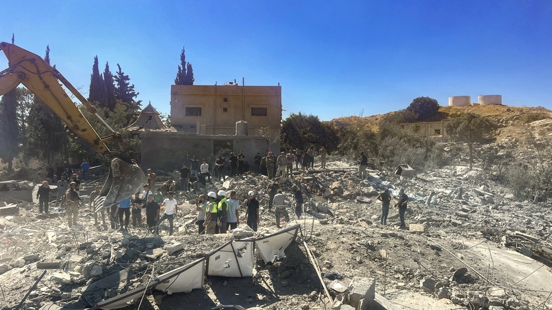 People check the rubble of destroyed buildings in Lebanon's Bekaa Valley village of Younine after at least 23 Syrians were killed