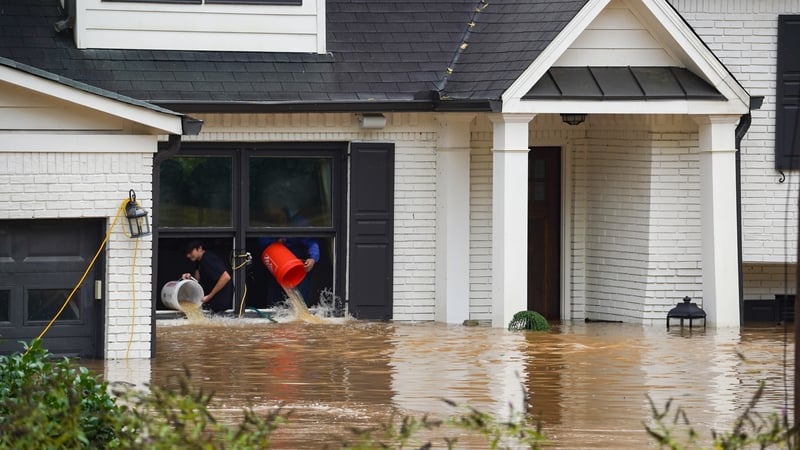 People toss buckets of water out of a home as the streets and homes are flooded near Peachtree Creek in Georgia