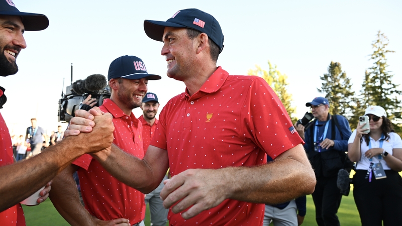 Keegan Bradley shakes hands with Scottie Scheffler after defeating Kim Si-woo of the International Team