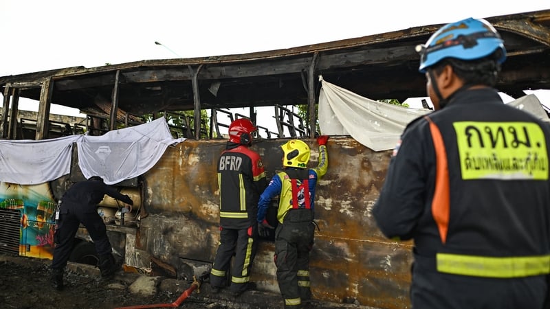 Firefighters and rescue workers inspect the wreckage of the bus