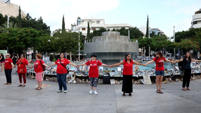 People hold hands at a memorial event marking the anniversary in Tel Aviv today