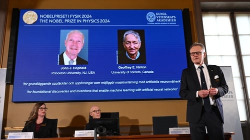 A screen shows the laureates of the 2024 Nobel Prize as member of the Nobel Committee for Physics Anders Irbaeck (R) delivers a speech