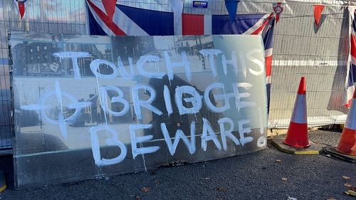 The sign has been removed from a fence at one end of the bridge