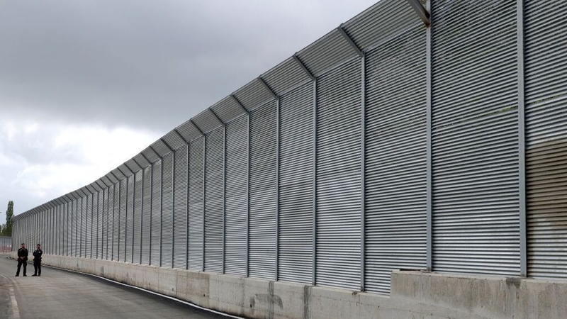 Italian police officers outside the fence of a recently build Italian-run migrant centre at the port of Shengjin, Albania