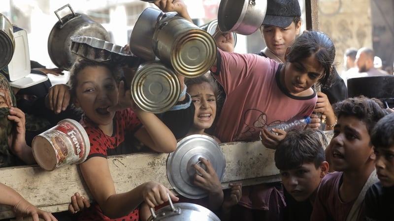 Palestinians, who took refuge at Nuseirat refugee camp due to Israeli attacks, wait in queue to receive food in Gaza city