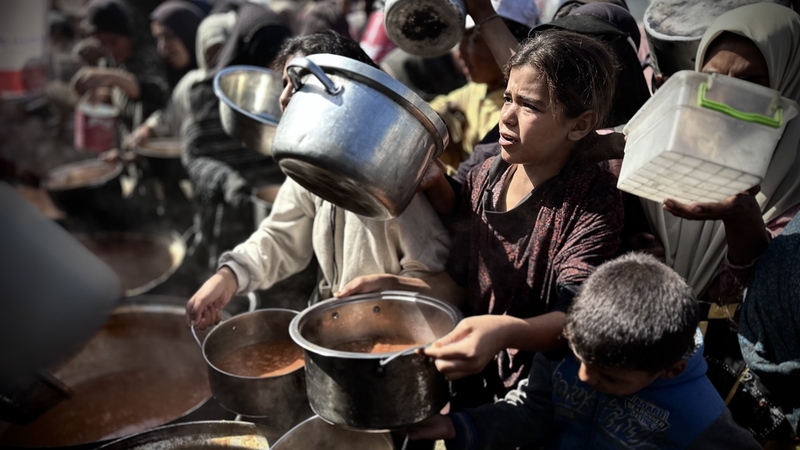 Palestinian children wait in line to receive food in Khan Younis