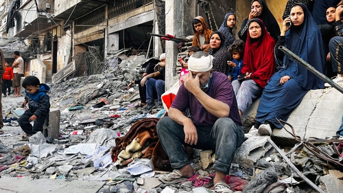 An injured man sits on the rubble of a building destroyed following an Israeli strike in Beit Lahia