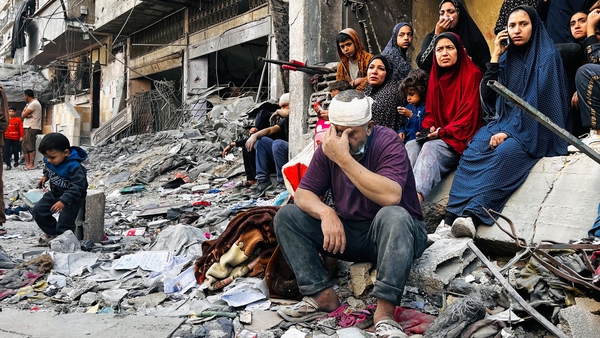 An injured man sits on the rubble of a building destroyed following an Israeli strike in Beit Lahia