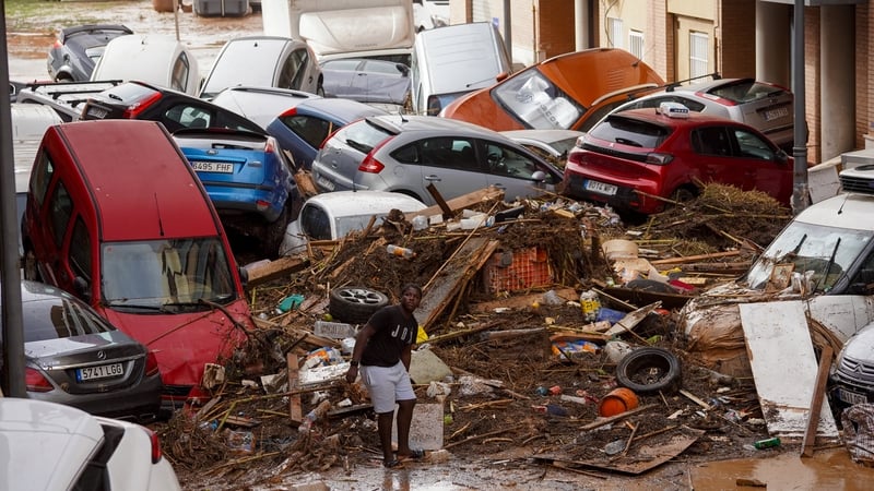 A boy stands among cars and debris after flash floods tore through Valencia