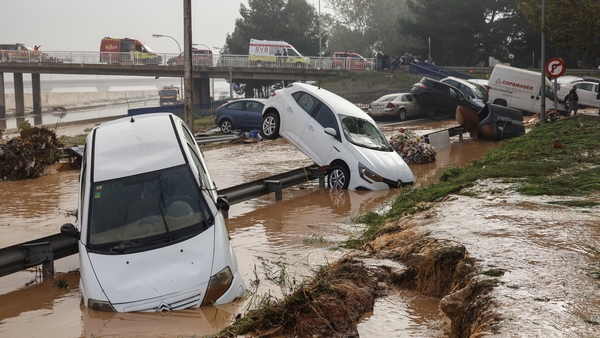 Cars are suspended over rails during heavy flooding in the Valencia region of Spain