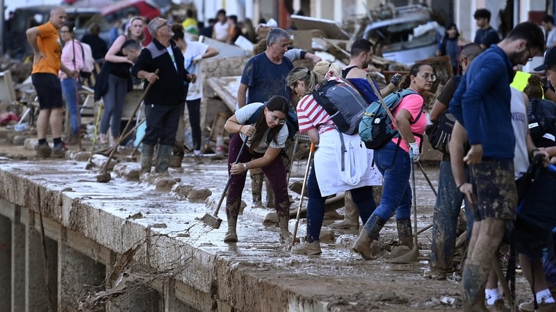 Locals and volunteers remove muddy water after flooding devastated the town of Paiporta in the Spanish region of Valencia