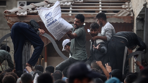 Palestinians scramble to receive sacks of flour at a United Nations Relief and Works Agency aid distribution centre amid the Israel-Hamas conflict in Deir Al-Balah, Gaza