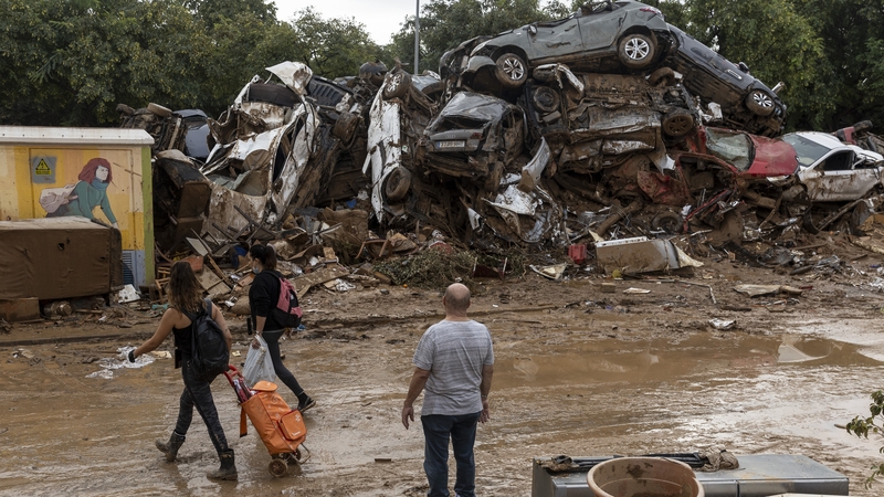 A man looks at a pile of cars after heavy rain and flooding hit large parts of the country in Alfafar