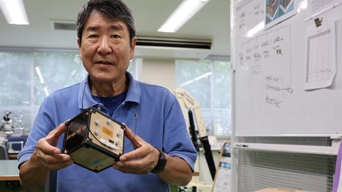 Professor Takao Doi holding a model of the satellite