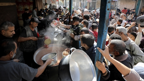 Palestinians living in Nuseirat refugee camp wait to receive food distributed by an aid organisation