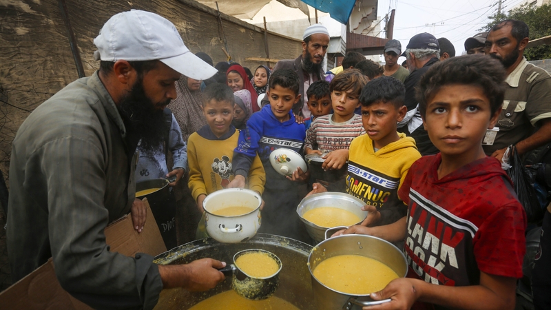 Palestinian children wait to receive food distributed by an aid organisation in central Gaza