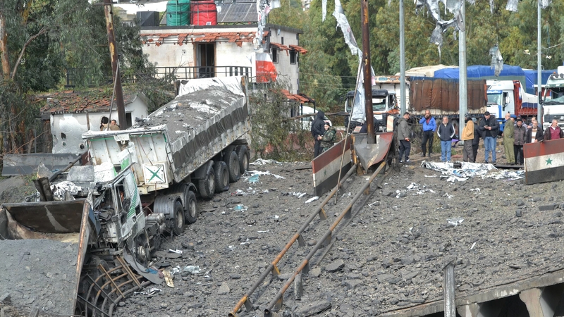 A picture taken from Lebanon shows Syrian officials inspecting the damage on the Syrian side of the Dabussiyeh border crossing after an Israeli airstrike