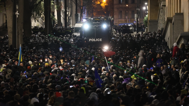 Riot police equipped with shields and a water cannon vehicle confront protesters gathered near the Parliament building in Tbilisi