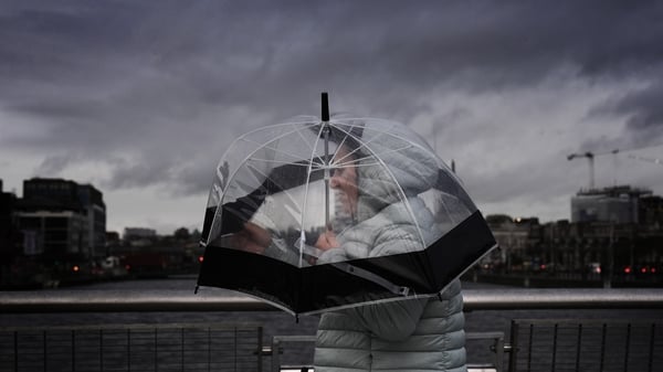 A person takes shelter under an umbrella as they cross O'Casey Bridge in Dublin's city centre