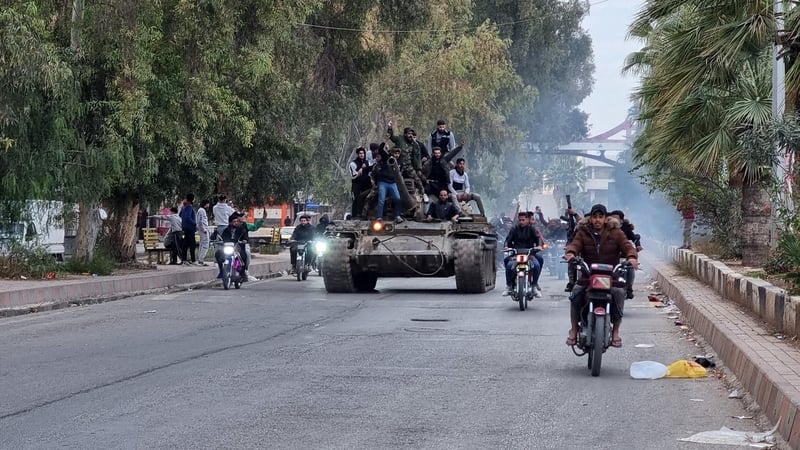 People ride a tank in the Syrian city of Daraa