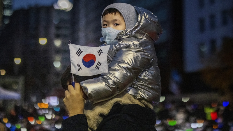 A child carried by his father in a demonstration against the President Yoon outside the National Assembly in Seoul