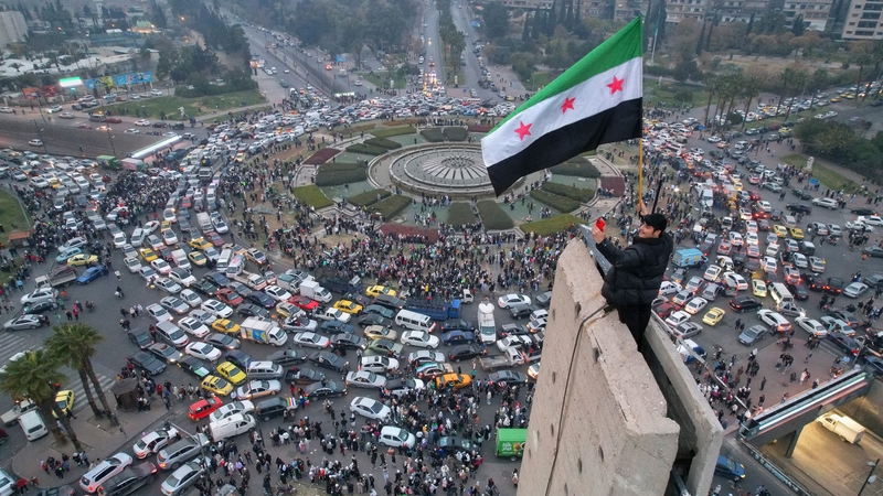 A Syrian man waving the independence-era Syrian flag over Umayyad Square in Damascus