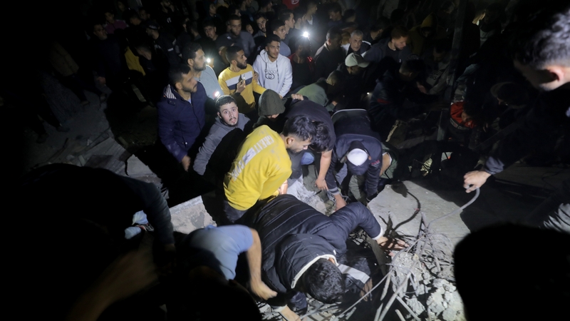Palestinians and civil defence teams conduct search and rescue operations on the debris of a building after an Israeli airstrike, which killed 21 Palestinians, in Nuseirat Camp in Gaza