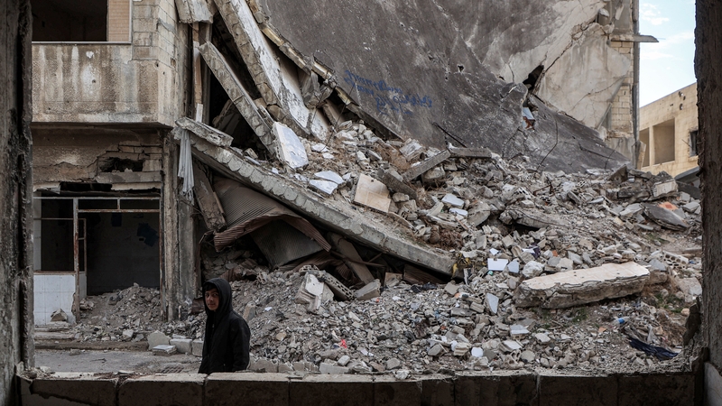 A boy walks past a collapsed building in the Baba Amr district of Homs, Syria