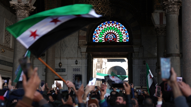 Syrians wave the independence-era flag after Friday Noon prayers at the Umayyad Mosque in the capital Damascus