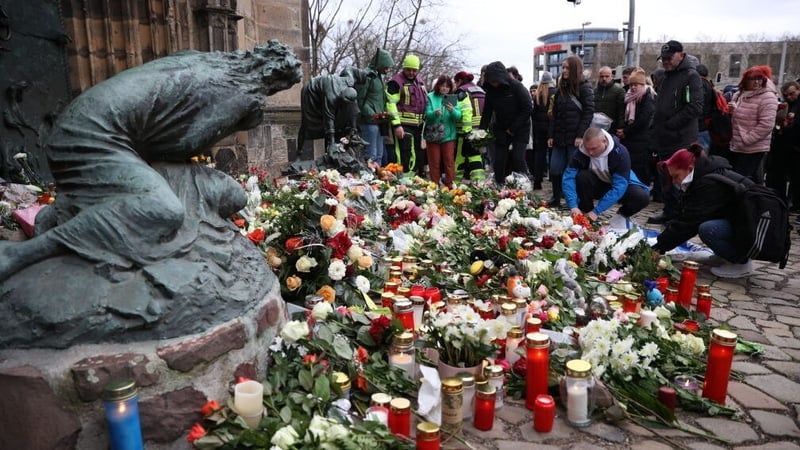 People lay flowers and candles at the site of the car-ramming attack on a Christmas market in Magdeburg
