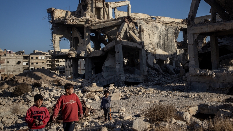 Boys walk in front of the destroyed Sakina Shrine in Daraya suburb, Damascus