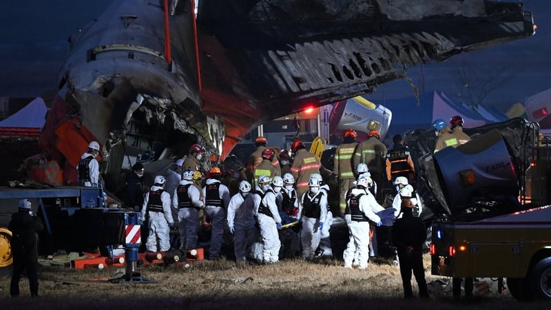 Firefighters and rescue personnel carry the body of a victim near the scene where a Jeju Air Boeing 737-800 series aircraft crashed and burst into flames