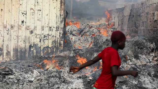 A woman runs past flames after the second-hand clothes market at Accra, Ghana, went on fire displacing thousands of traders