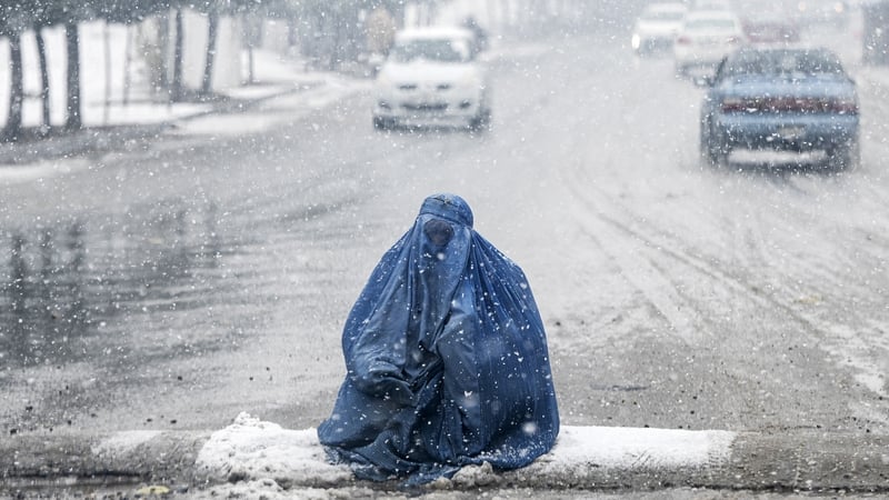 A woman is seeing begging for alms during the first heavy snowfall this winter in Kabul, Afghanistan