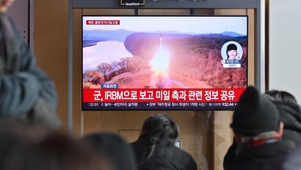 People watch a television showing a news broadcast with file footage of a North Korean missile test