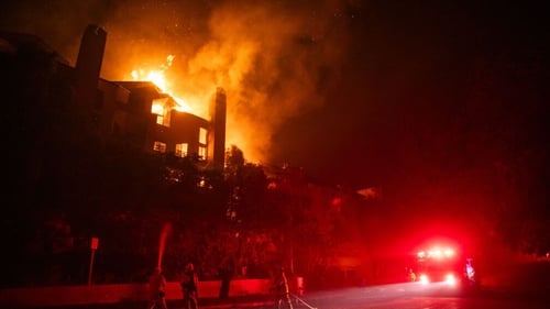 Flames from the Palisades fire burns a residential building at Sunset Boulevard