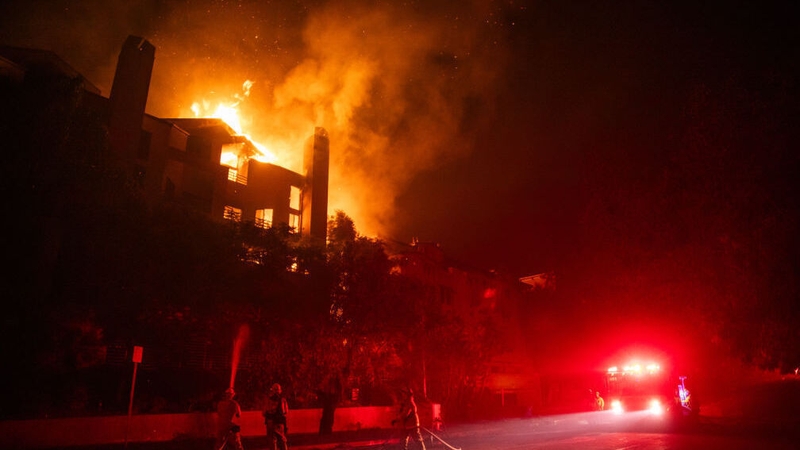 Flames from the Palisades fire burns a residential building at Sunset Boulevard