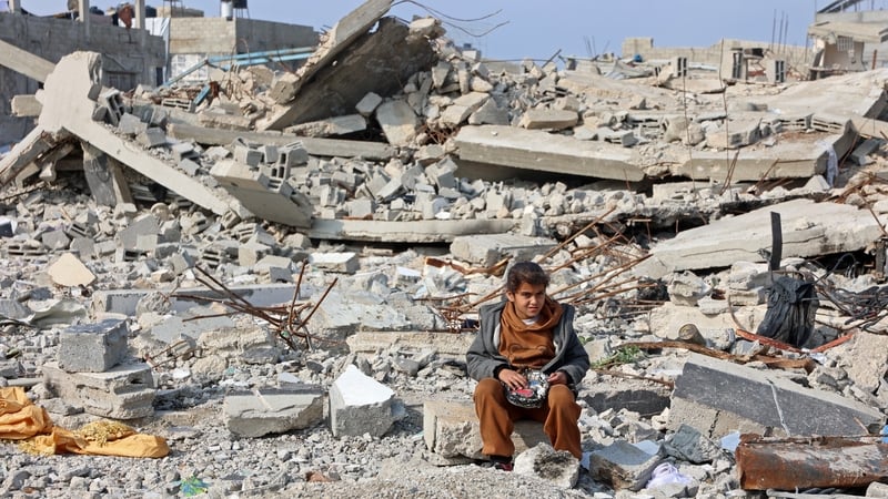 A Palestinian girl sits amid the rubble of buildings destroyed in Israeli airstrikes as ceasefire talks continue