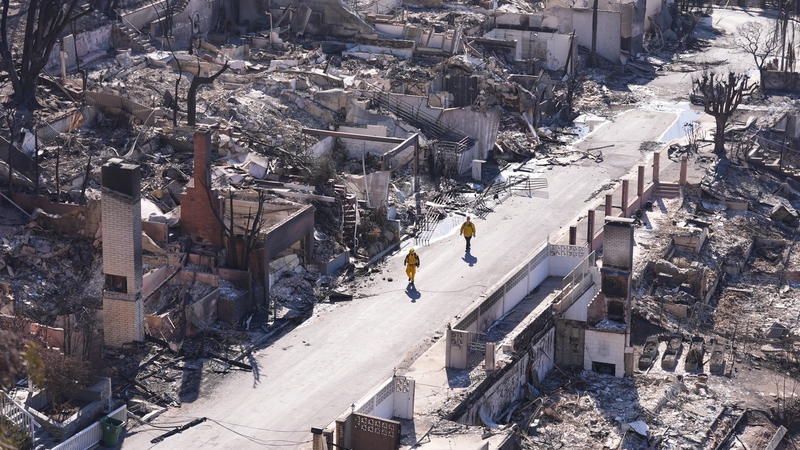 Firefighters walk through a ruined neighbourhood in LA