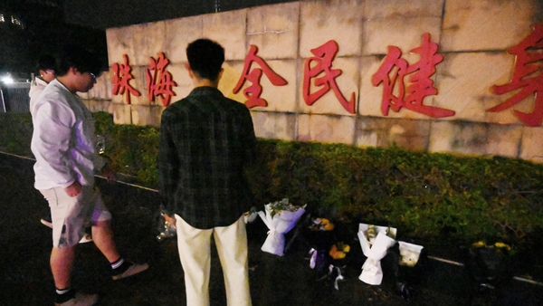 Men leave flowers at a memorial outside the Zhuhai Sports Centre after the incident in which 35 people were killed