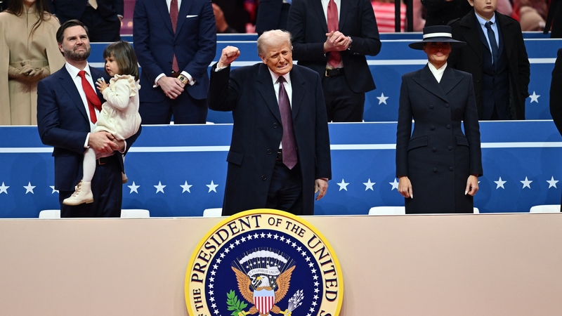 US President Donald Trump gestures alongside US First Lady Melania Trump and US Vice President JD Vance during the inaugural parade inside Capital One Arena